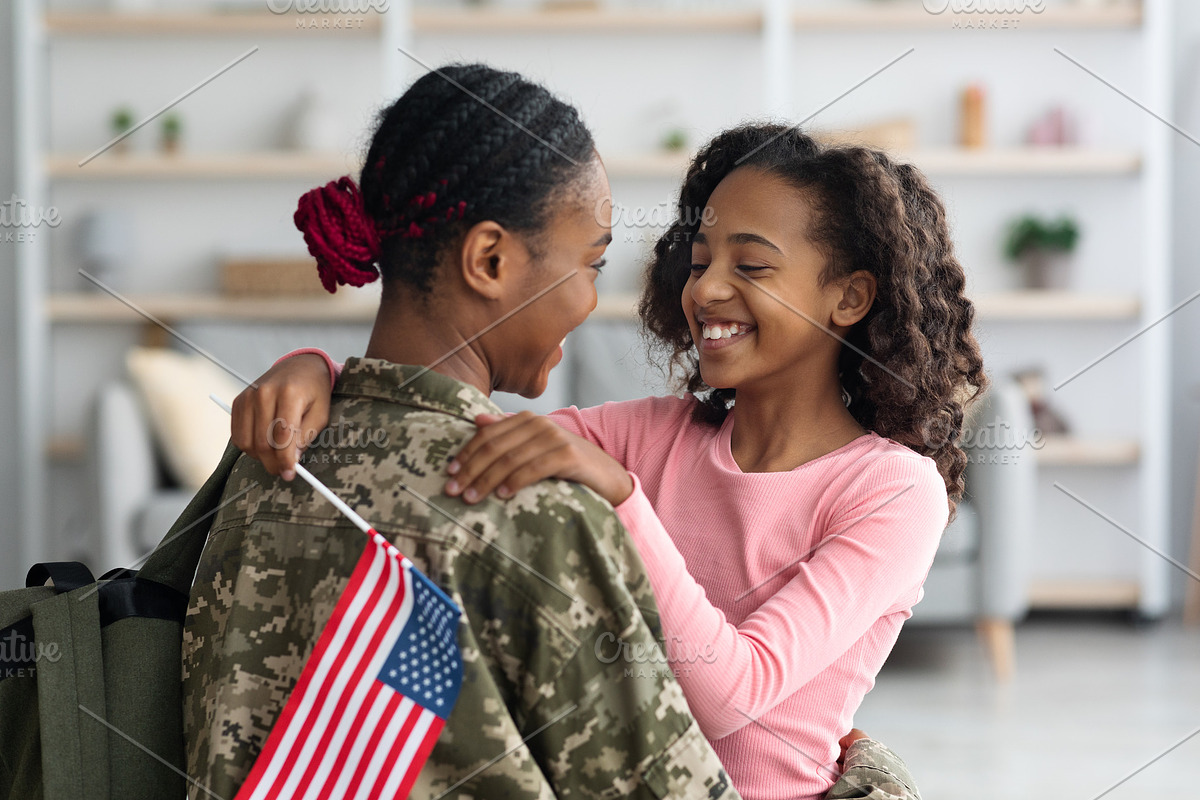 Cheerful girl with flag of the US hugging her mom, a Photo by Prostock-Studio (Photo 2 of 2)