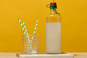 A transparent glass bottle of lemonade stands next to a faceted, a Food & Drink Photo by ndanko