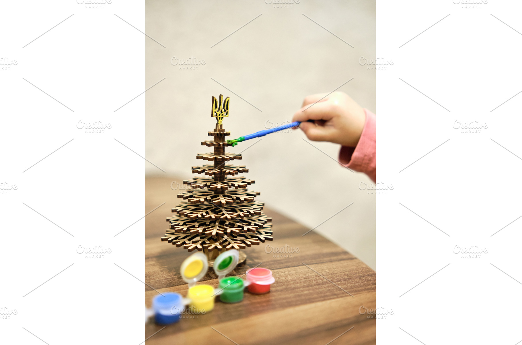 A little girl paints a wooden toy in, a Holiday Photo by Rohan Photography