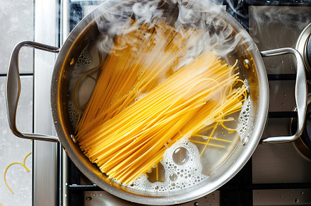 Flat lay of spaghetti cooking in boiling water, a Food & Drink Photo by AlyaAnd