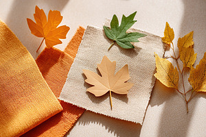 Autumn leaf cutouts arranged on fabric mockup showcasing seasonal design elemen, a Beauty & Fashion Photo by AlyaAnd