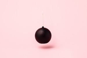 Minimalist black bomb with white fuse suspended against pastel p, an Abstract Photo by Ales Munt