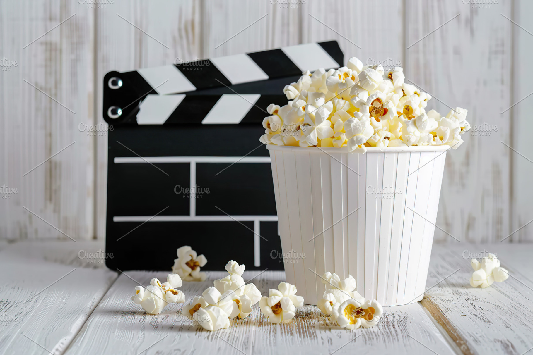 Black clapper board and bucket of popcorn on wooden background, a Food & Drink Photo by AlyaAnd