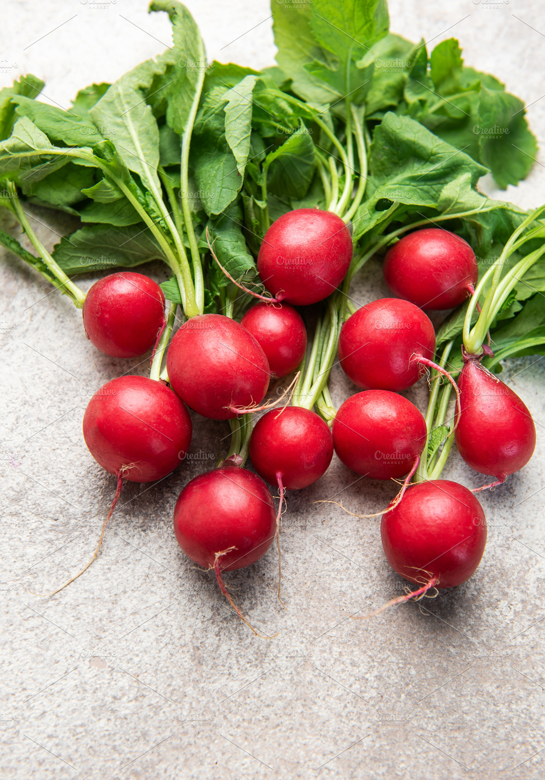 Fresh harvested red radishes with green leaves on concrete, a Food & Drink Photo by Olena Rudo