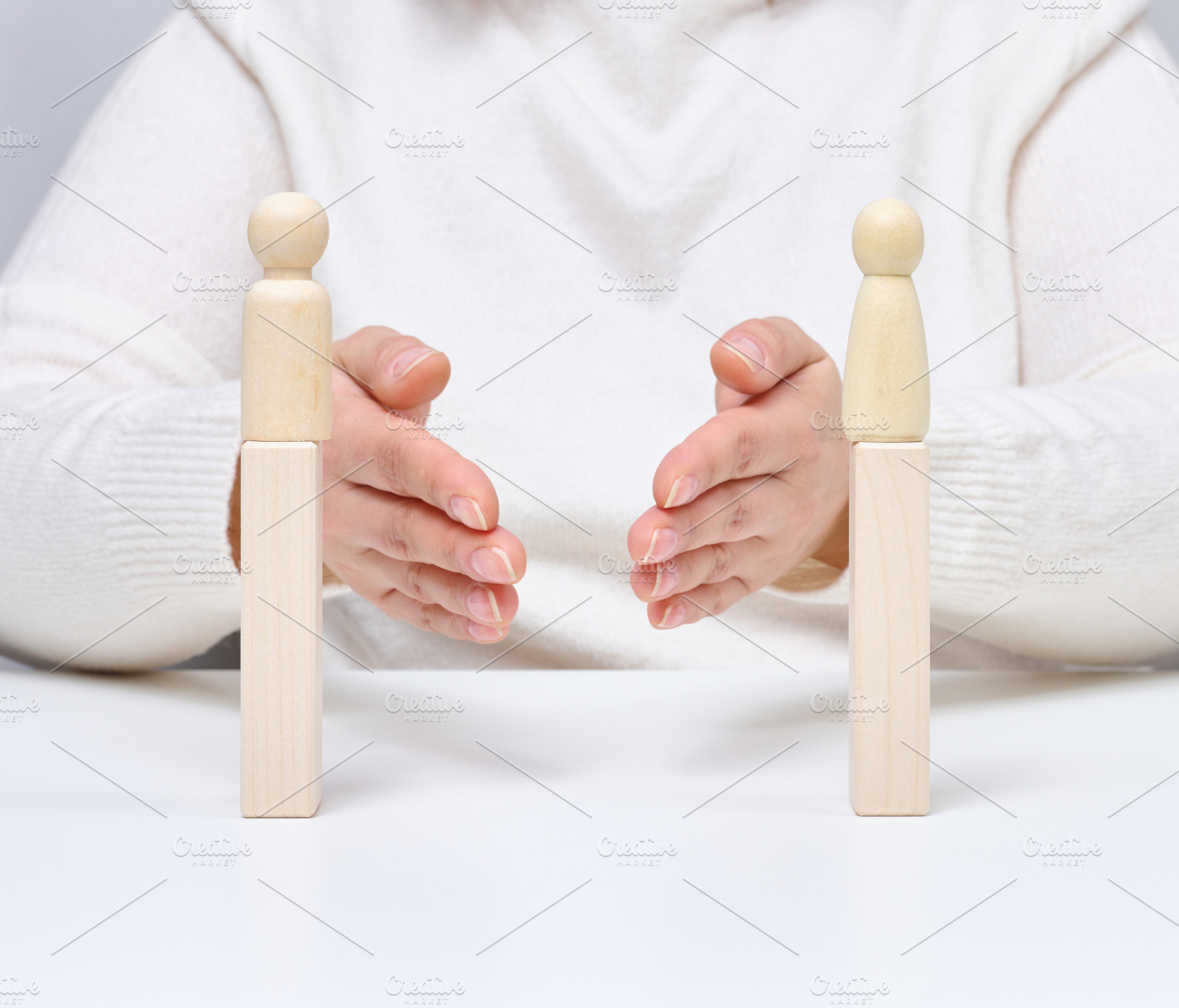 A man uses his hands to bring together two wooden figures on sta, a Person Photo by ndanko