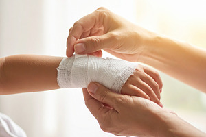 Adult hand placing a bandage on a child  wrist, a Person Photo by DanFLCreativo
