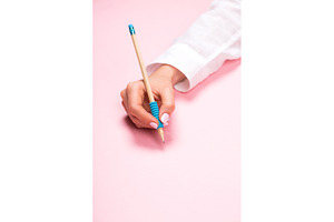 Hand holding pencil on pink, a Business Photo by Anna Efetova