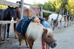 A small smiling girl with curly hair stock photo containing stable and horse