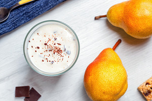 Yogurt with grated chocolate and pears on white wooden table enjoying a healthy, a Food & Drink Photo by Antonio Gravante Market