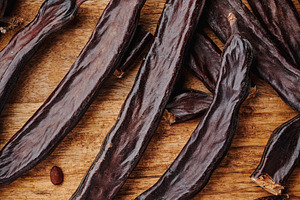 closeup of some ripe carob pods on a table, a Photo by Nito
