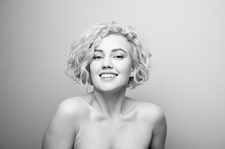 Headshot of gorgeous attractive young lady with curly hair smiling. Black and w
