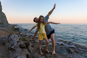 Happy father and daughter playing together on rocky beach at sunset, enjoying f, a Person Photo by Ales Munt