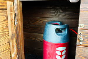 Wooden cupboard with a red gas cylinder safely stored inside, a Photo by AS photostudio