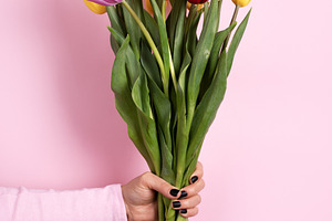 Hand holding a vibrant bouquet of tulips in red, yellow, and pin, a Holiday Photo by Ales Munt