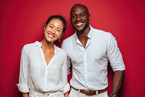 Smiling couple in matching white outfits against a bright red background indoor, a Person Photo by AlyaAnd