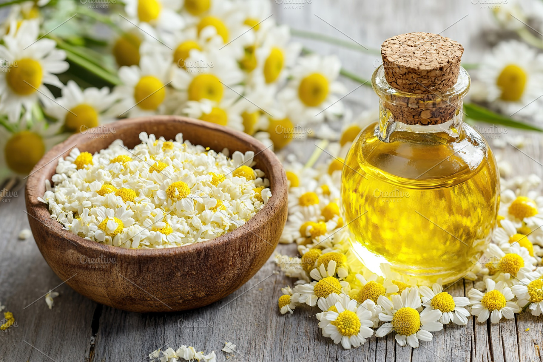 Bottle of essential oil with chamomile flowers on wooden background, a Nature Photo by AlyaAnd
