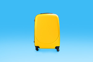Yellow stylish suitcase isolated over blue studio background wall, a Photo by Prostock-Studio