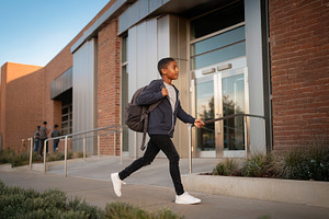 Black middle school student walking toward a school entrance wit, a School & Education Photo by DanFLCreativo