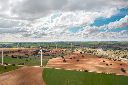 Wind turbines spinning across open countryside under cloudy sky