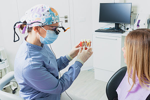 Dentist showing denture model to patient in clinic, a Health & Medical Photo by Antonio Gravante Market