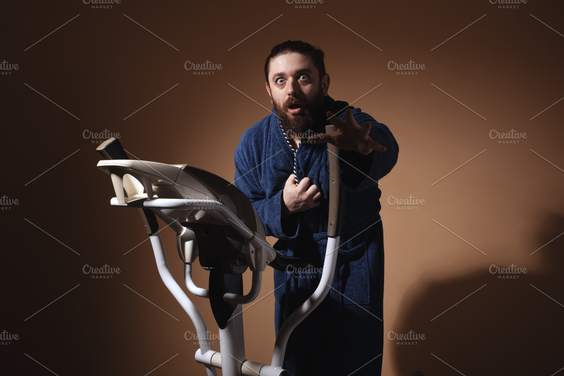 Surprised man in a blue bathrobe using an exercise bike against, a Person Photo by Ales Munt