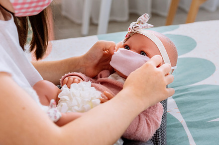 Girl with mask putting small mask on her doll, a Person Photo by davidpereiras