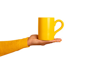 A person's hand in a yellow sleeve holds a bright yellow ceramic, a Food & Drink Photo by Ales Munt