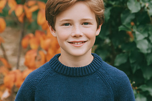 Young boy smiling directly at the camera while standing outdoors, a Photo by Studio ANNA