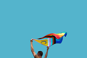 man is waving a progress pride flag outdoors, a Person Photo by Nito