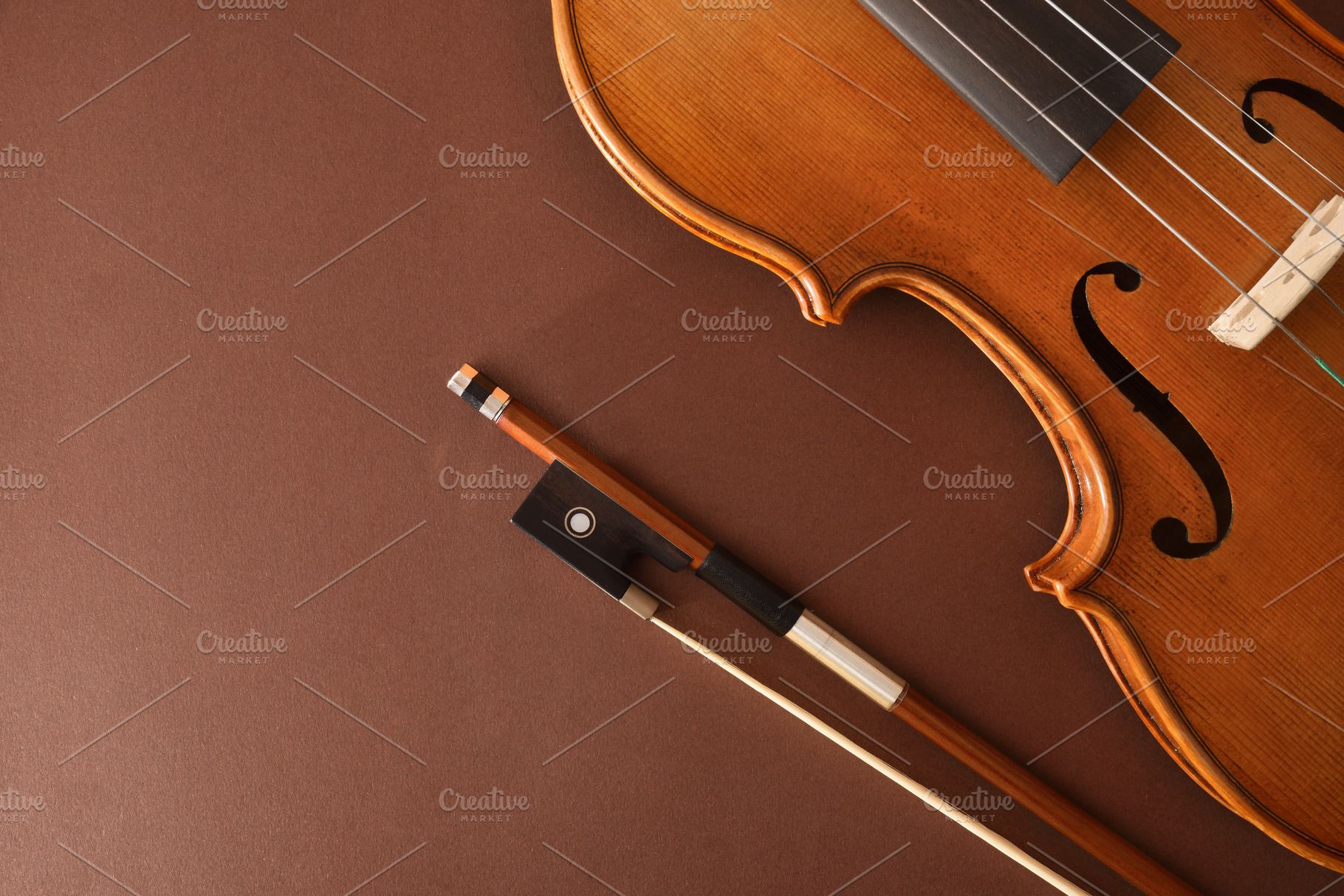 Traditional stringed violin and bow placed diagonally on brown b, an Arts & Entertainment Photo by Davizro's Market