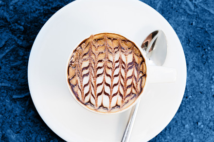 Cup of coffee with latte art on blue, a Photo by Kate Molchanova