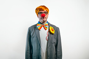 Clown in suit wearing red nose and bowtie, a Person Photo by karrastock