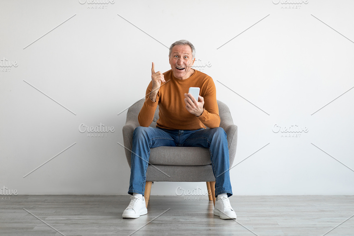 Portrait of mature man using smartphone sitting on armchair, a Photo by Prostock-Studio (Photo 1 of 2)