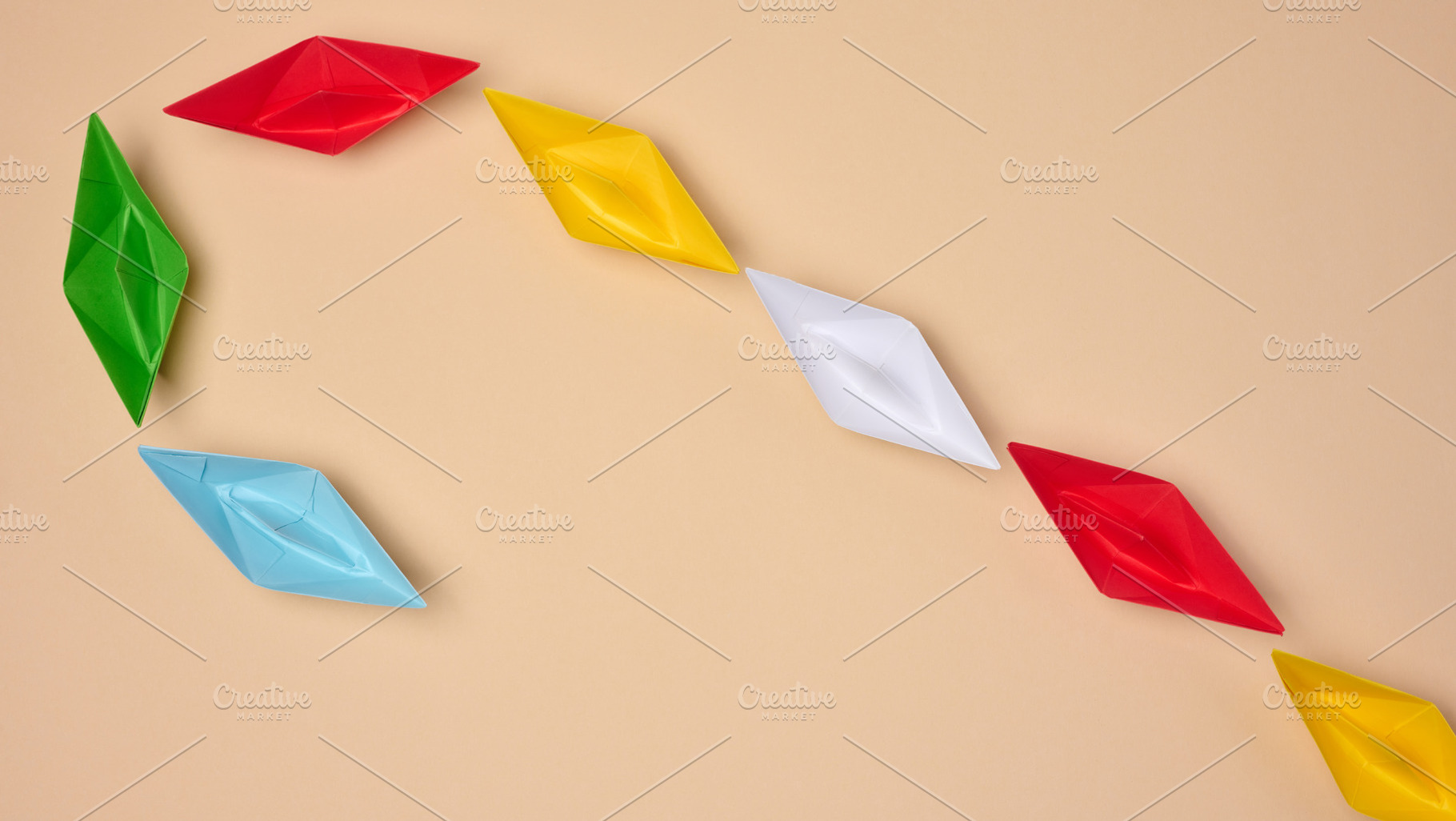 Multi-colored origami paper boats are arranged in a curved line,, a Business Photo by ndanko