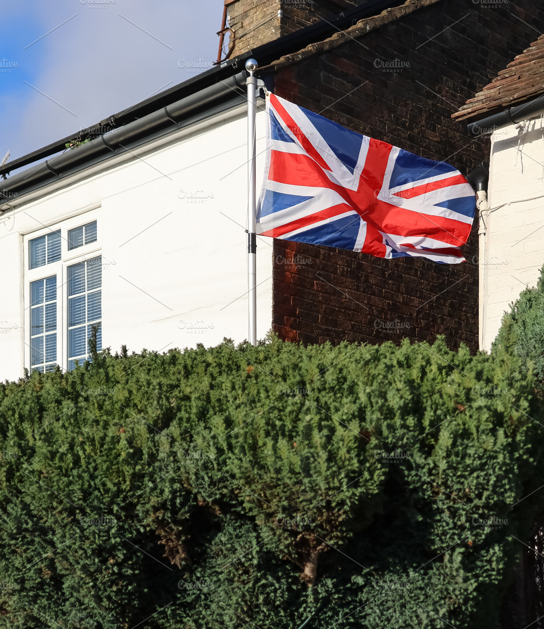 Union Jack flag flying high on a house, representing patriotism,, a Photo by Studio ANNA