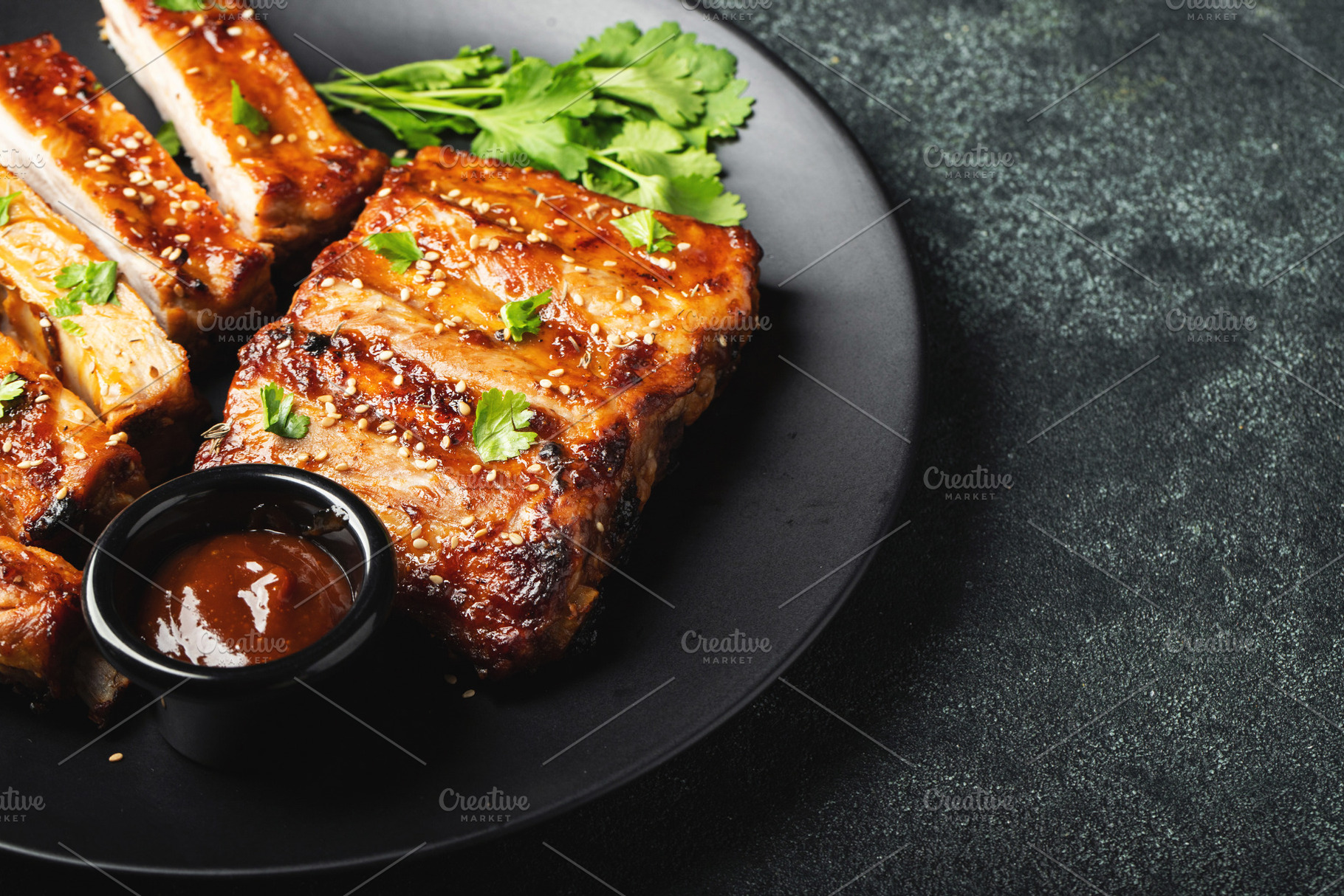 Hot grilled spare ribs from a summer BBQ served on a plate with sauce. Top view, a Food & Drink Photo by Budarinphoto