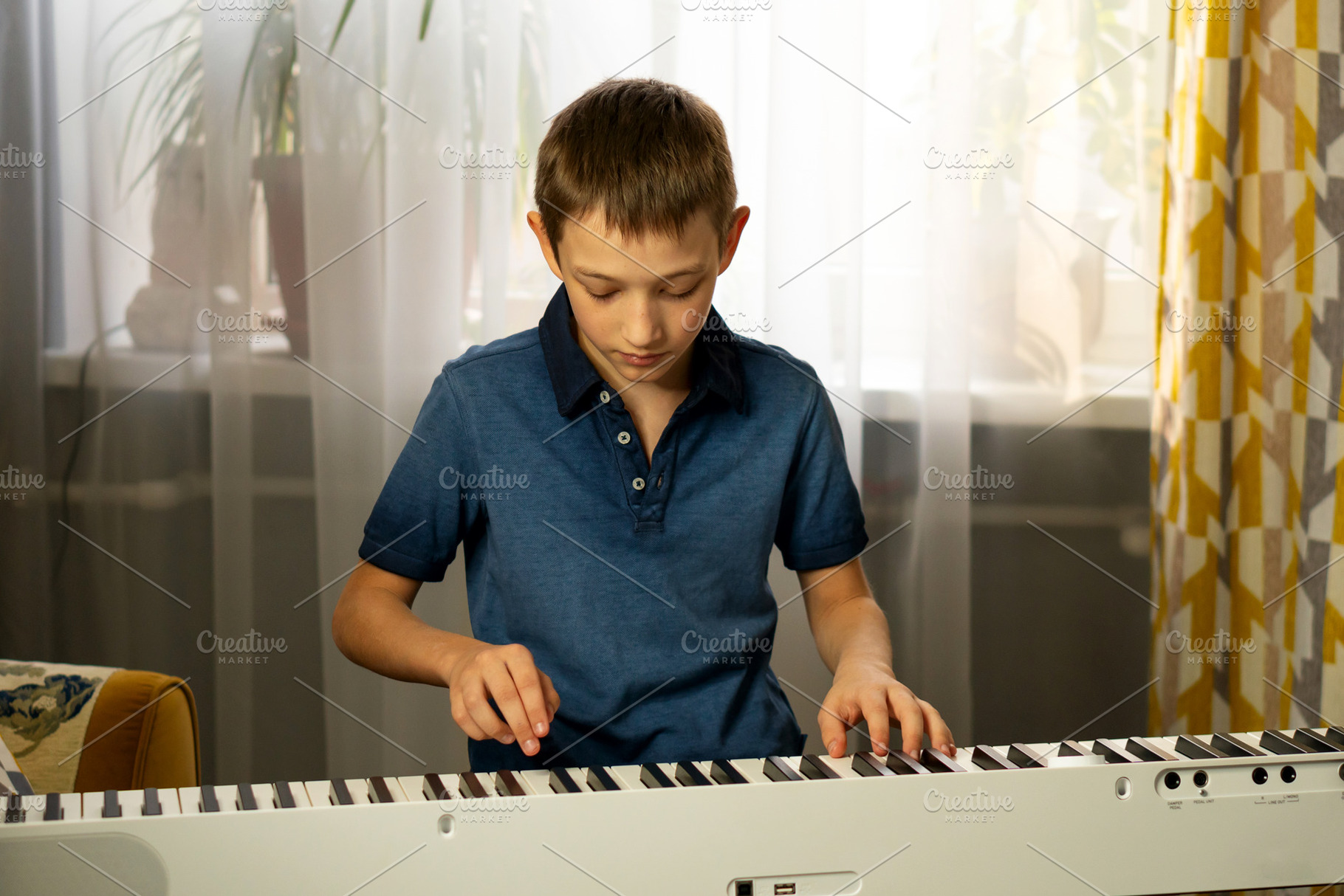 Boy in blue shirt playing piano, a School & Education Photo by Elena Vagengeim
