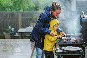 Mother and child cooking at rainy barbecue, a Person Photo by DanFLCreativo