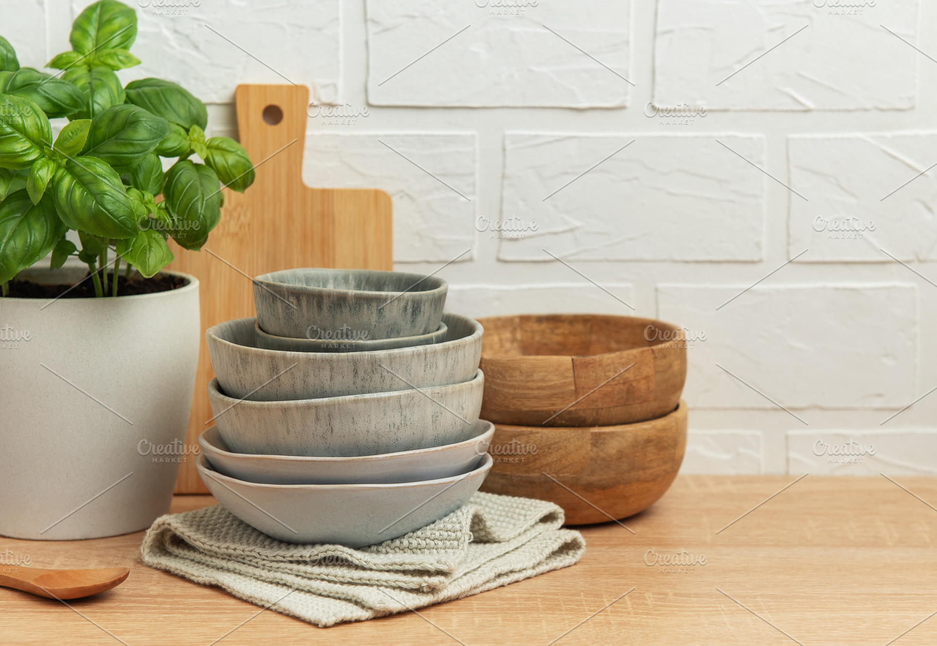 Kitchen table setting featuring stacked bowls, fresh basil, and, a Food & Drink Photo by Olena Rudo