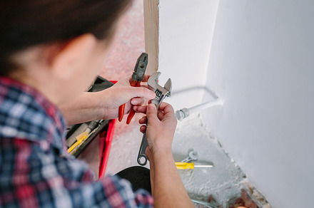 Female plumber adjusting spanner to install heating, an Industrial Photo by davidpereiras