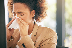 Business woman, sneeze and blowing nose with allergies, sick with virus or health issue while working at office. Corporate female, allergy and hayfever with illness, cold and flu with sinus problem, a Photo by Peopleimages.com