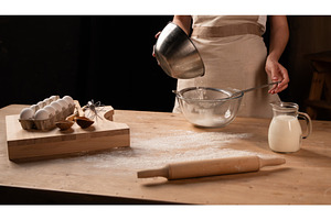 Woman sifting flour over a glass, a Food & Drink Photo by volodymyrshtun13795