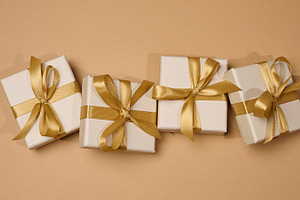 Boxes tied with golden ribbon on beige background, a Holiday Photo by ndanko