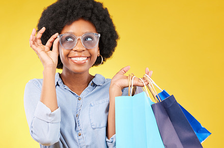 Fashion, smile and black woman with shopping bags, happy and excited for sale in studio on yellow background. Sunglasses, shopper and girl customer cheerful after boutique, retail or store discount, a Photo by Peopleimages.com