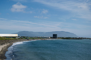 Scenic coastal view of Akranes beach with distant mountains under sunny sky, a Photo by AS photostudio