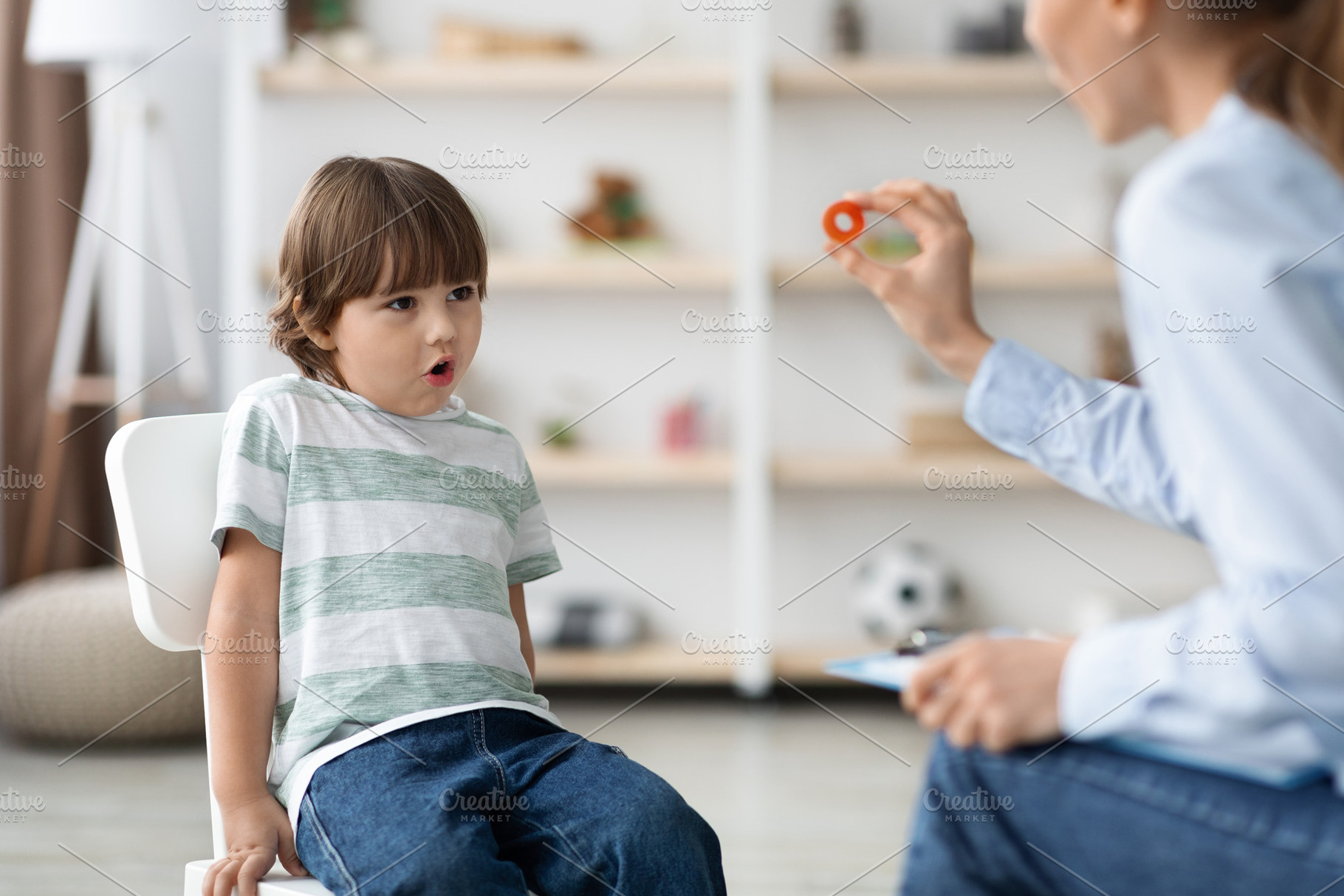 Cute little boy studying with professional woman speech therapist, pronouncing, a Photo by Prostock-Studio