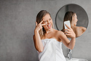 Playful woman taking selfie on smartphone while enjoying beauty morning routine, a Photo by Prostock-Studio (Thumbnail 3 of 3)