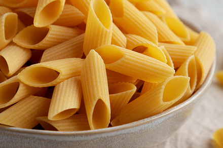Raw Organic Dry Pennoni Pasta in a Bowl, side view., a Food & Drink Photo by LiudmylaChuhunova