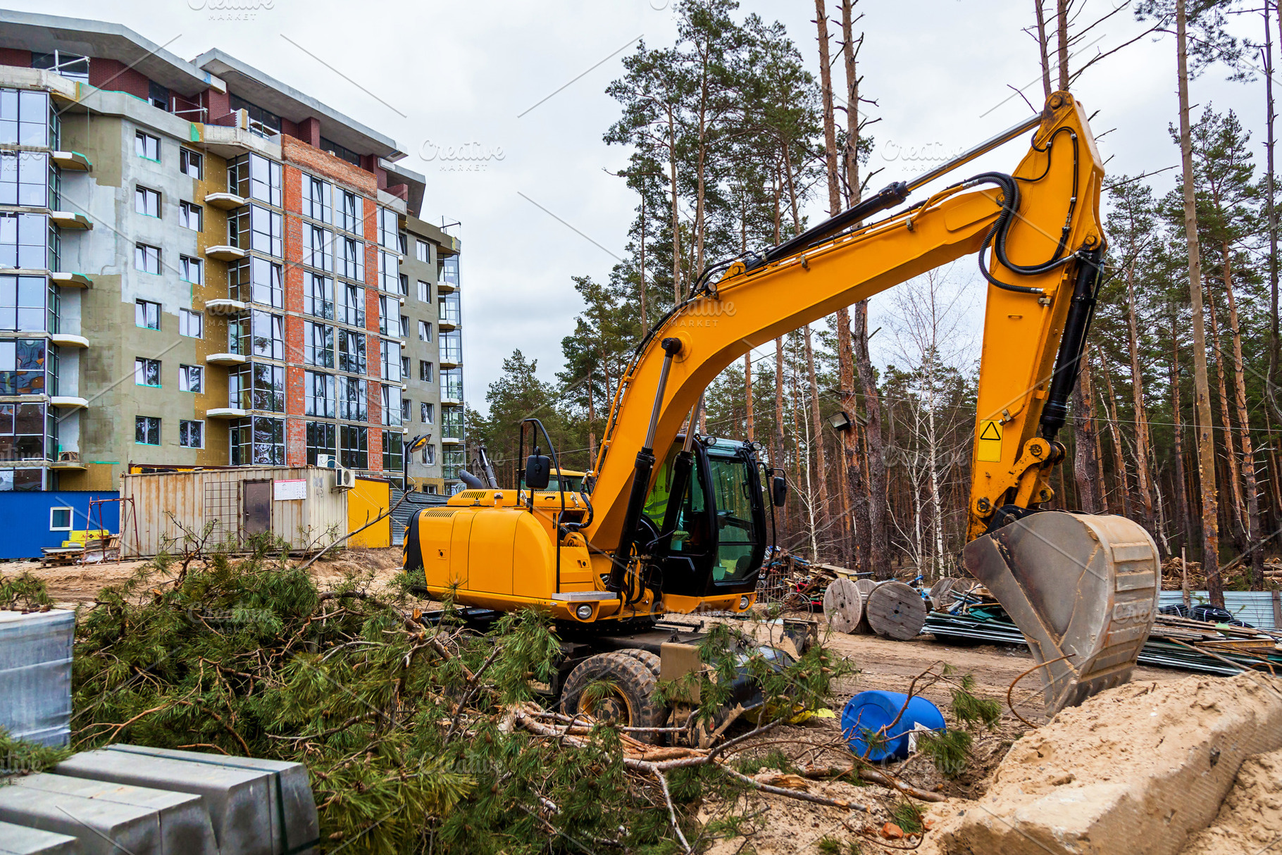 Yellow excavator at construction site near modern apartment, an Industrial Photo by Photostock
