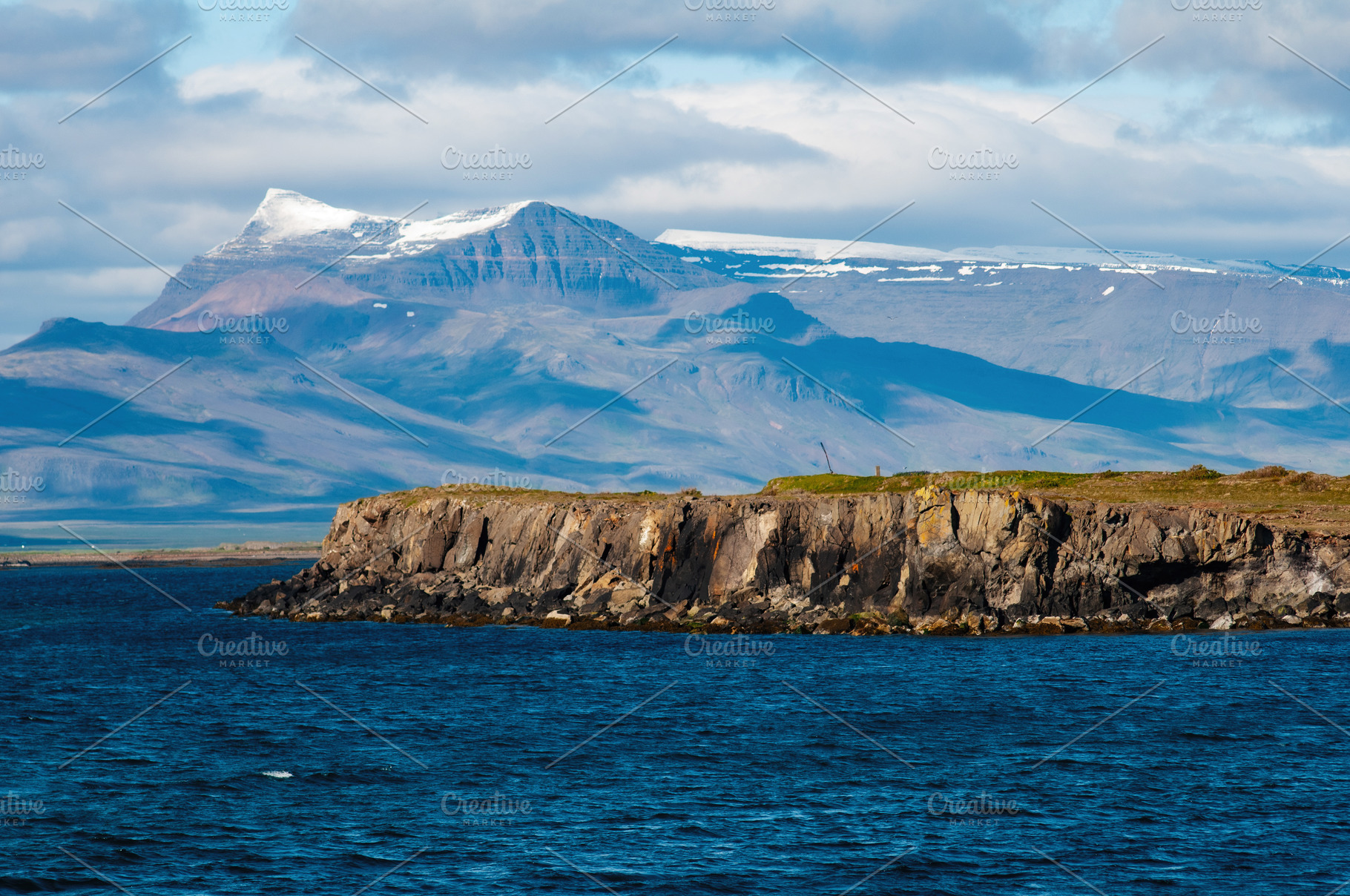 Rocky coastline with Akranes mountainscape and blue waters in Iceland, a Photo by AS photostudio